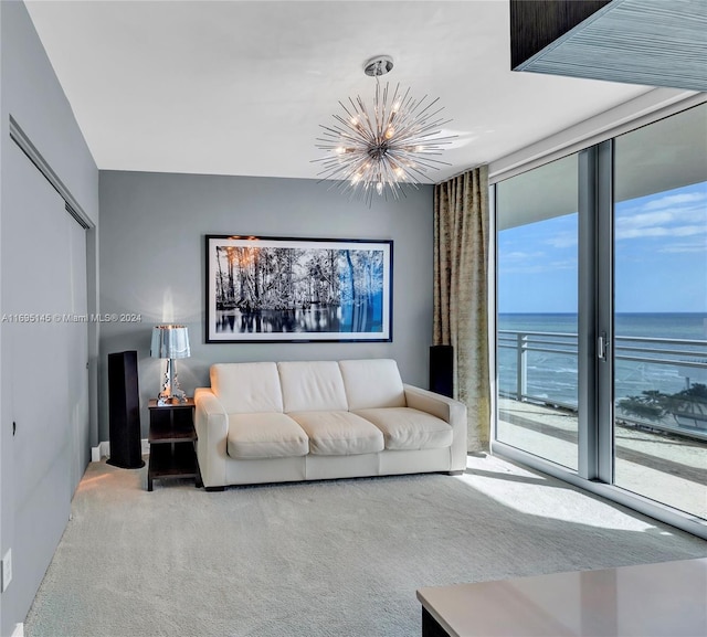 carpeted living room with a healthy amount of sunlight, a water view, and an inviting chandelier