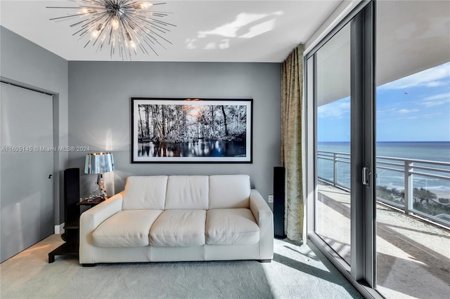 living room featuring carpet flooring, plenty of natural light, a water view, and a notable chandelier