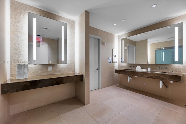 bathroom with tile patterned floors, double sink, and tile walls