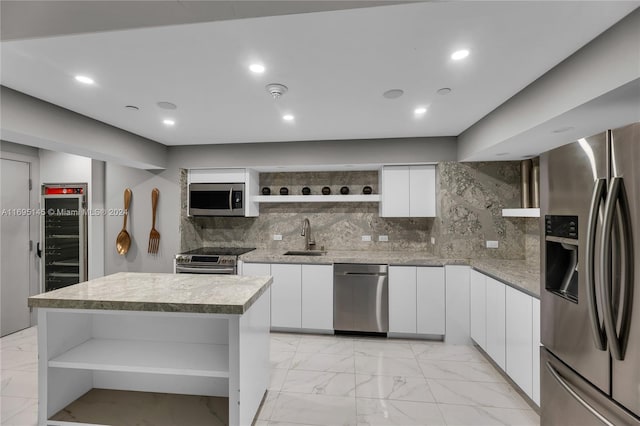 kitchen featuring appliances with stainless steel finishes, backsplash, a kitchen island, sink, and white cabinetry