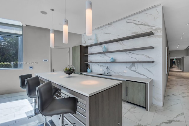 kitchen with a breakfast bar, pendant lighting, dark brown cabinets, and sink