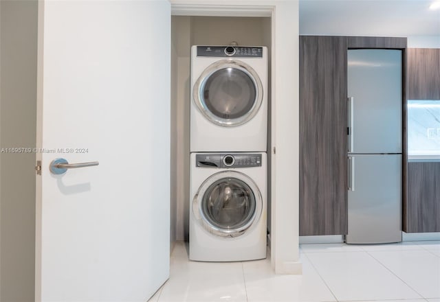 clothes washing area with light tile patterned floors and stacked washer and clothes dryer