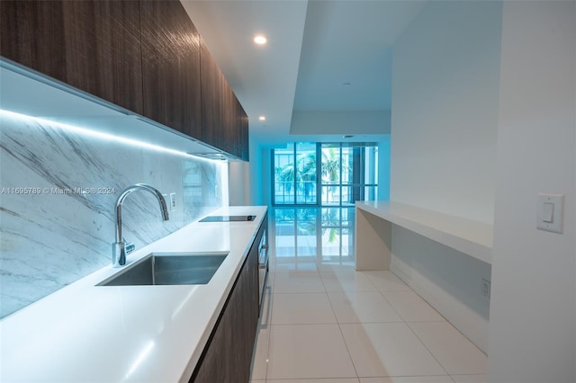 kitchen featuring dark brown cabinetry, sink, light tile patterned floors, and black electric stovetop