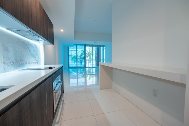 kitchen with black electric stovetop, dark brown cabinets, light tile patterned flooring, and stainless steel oven