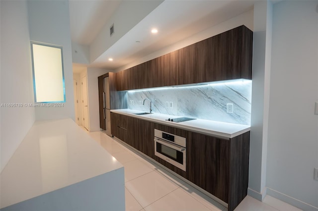 kitchen featuring black electric stovetop, oven, sink, decorative backsplash, and dark brown cabinetry