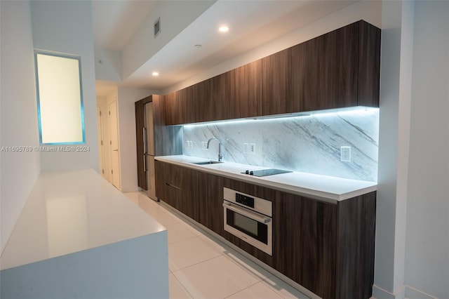 kitchen with tasteful backsplash, black electric cooktop, sink, light tile patterned floors, and oven