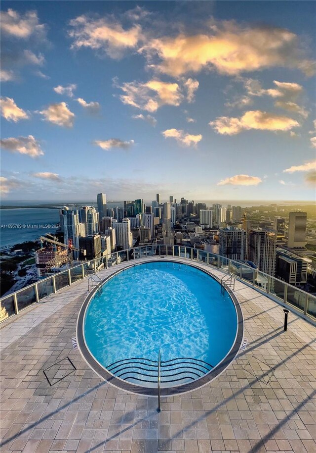 pool at dusk featuring a water view