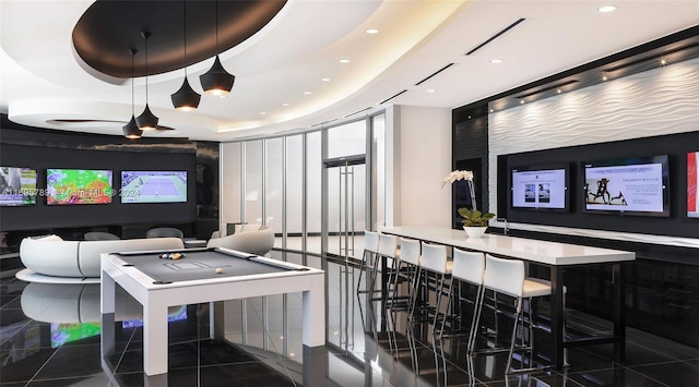 game room with a tray ceiling, dark tile patterned floors, and pool table