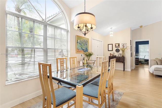 dining area with light hardwood / wood-style floors, a healthy amount of sunlight, and a notable chandelier