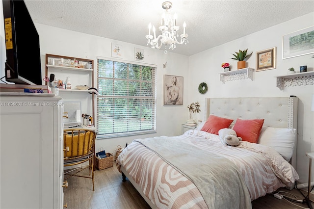 bedroom with a chandelier, wood-type flooring, and a textured ceiling