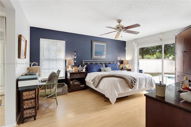 bedroom featuring access to exterior, a textured ceiling, light wood-type flooring, and ceiling fan