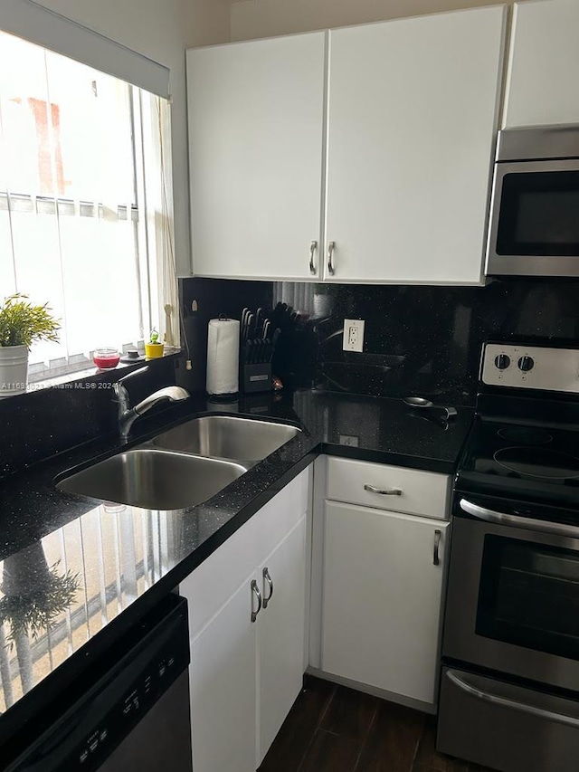 kitchen with appliances with stainless steel finishes, tasteful backsplash, sink, white cabinets, and dark hardwood / wood-style floors