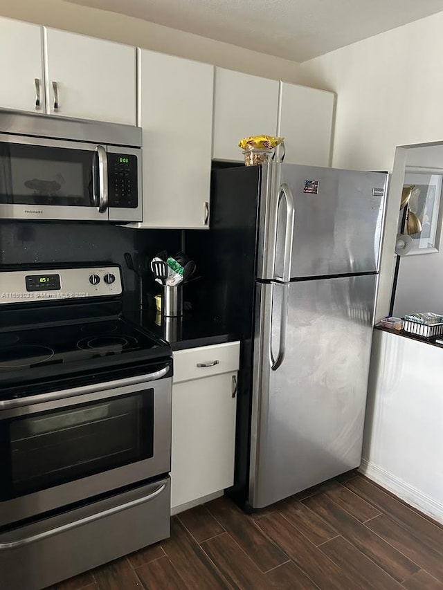 kitchen with white cabinets, stainless steel appliances, and dark wood-type flooring