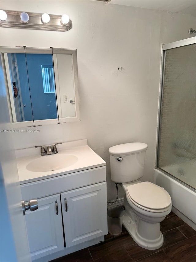 full bathroom with wood-type flooring, vanity, toilet, and bath / shower combo with glass door