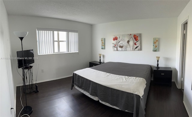 bedroom featuring dark wood-type flooring and a textured ceiling