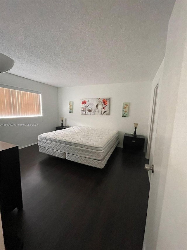 bedroom featuring dark hardwood / wood-style floors and a textured ceiling