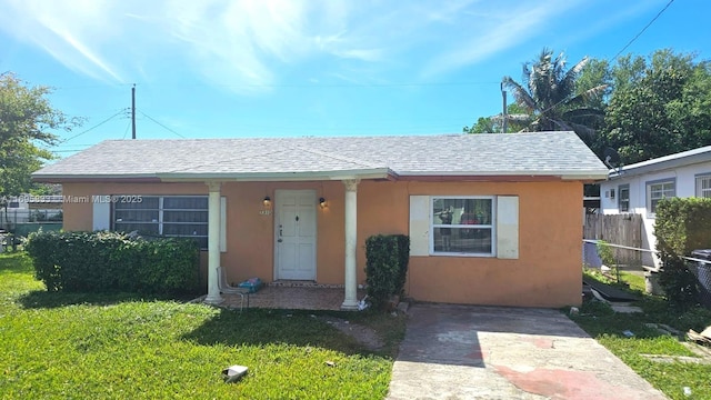 bungalow-style home with a shingled roof, a front yard, fence, and stucco siding