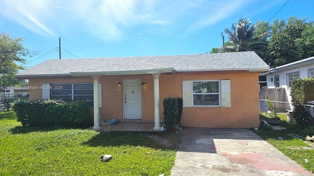 bungalow with a shingled roof, a front yard, fence, and stucco siding