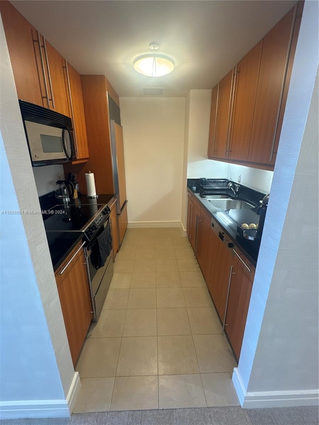 kitchen featuring stainless steel electric stove, sink, and light tile patterned floors