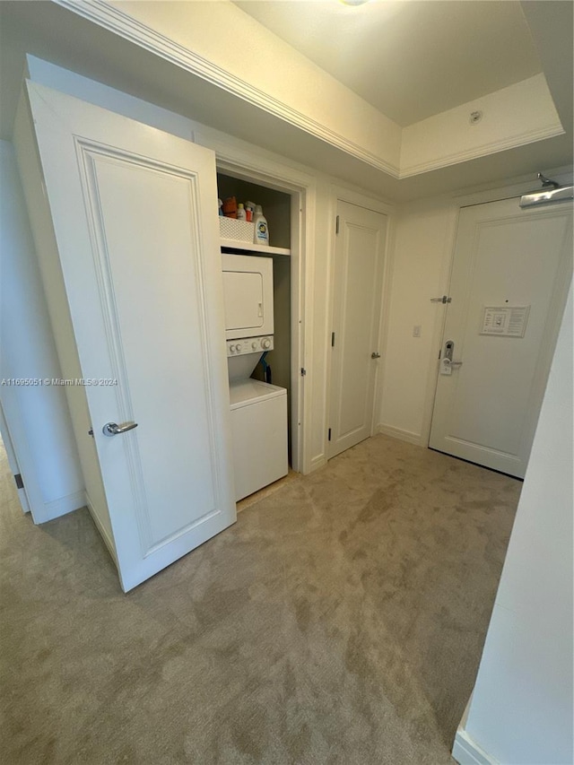 clothes washing area featuring light colored carpet and stacked washing maching and dryer