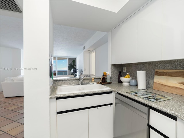 kitchen featuring tasteful backsplash, sink, white cabinets, and light tile patterned flooring