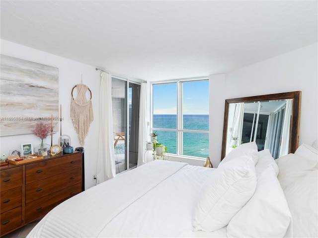 bedroom with access to outside, expansive windows, and a water view