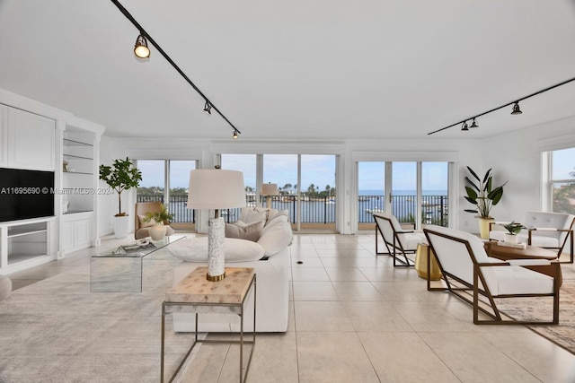 living room with a water view, light tile patterned flooring, and track lighting