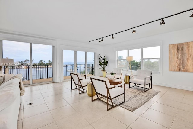 living room with a wealth of natural light, a water view, light tile patterned floors, and rail lighting