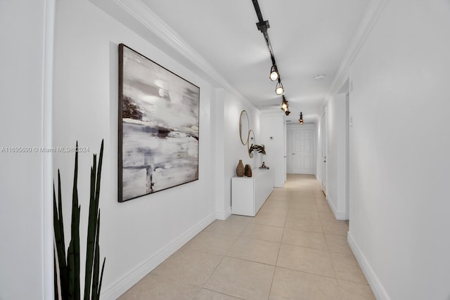 hallway featuring crown molding, light tile patterned floors, and track lighting