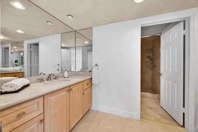 bathroom featuring tiled shower, vanity, and tile patterned floors