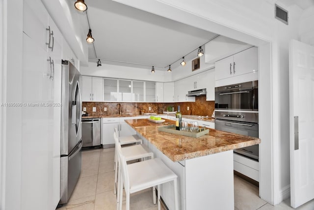 kitchen featuring a kitchen bar, white cabinetry, a kitchen island, and tasteful backsplash