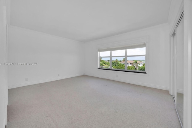 spare room with baseboards, crown molding, and light colored carpet