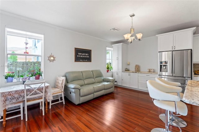 living room featuring crown molding, plenty of natural light, dark wood-type flooring, and a notable chandelier