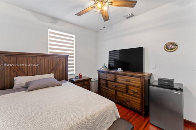 bedroom with stainless steel fridge, ceiling fan, and dark hardwood / wood-style floors