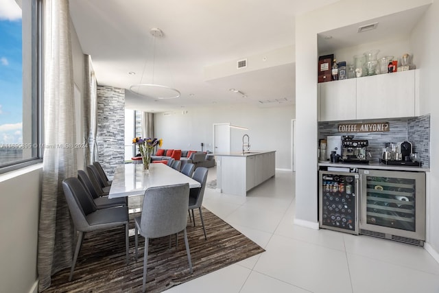 dining area with a healthy amount of sunlight, wet bar, light tile patterned floors, and beverage cooler