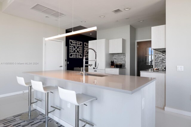 kitchen featuring a center island with sink, a breakfast bar, decorative backsplash, and sink