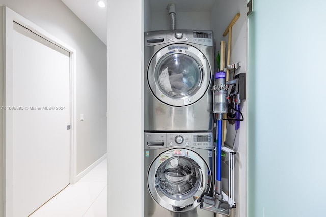 laundry area with light tile patterned floors and stacked washer and dryer