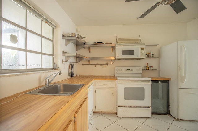 kitchen featuring white appliances, sink, light tile patterned floors, and wooden counters