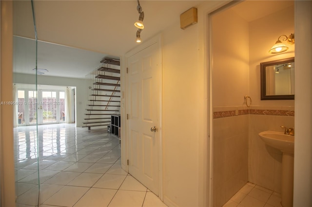 hall with sink, tile walls, and light tile patterned flooring