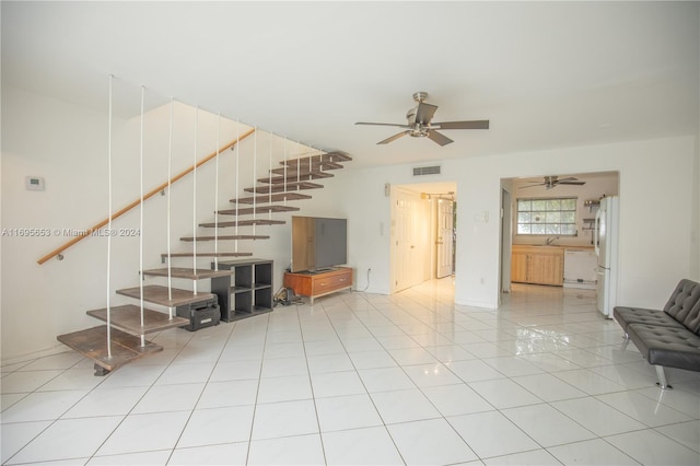 unfurnished living room featuring ceiling fan, light tile patterned flooring, and sink