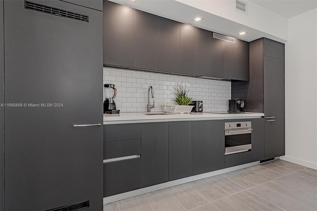 kitchen featuring decorative backsplash, appliances with stainless steel finishes, sink, light tile patterned floors, and gray cabinets