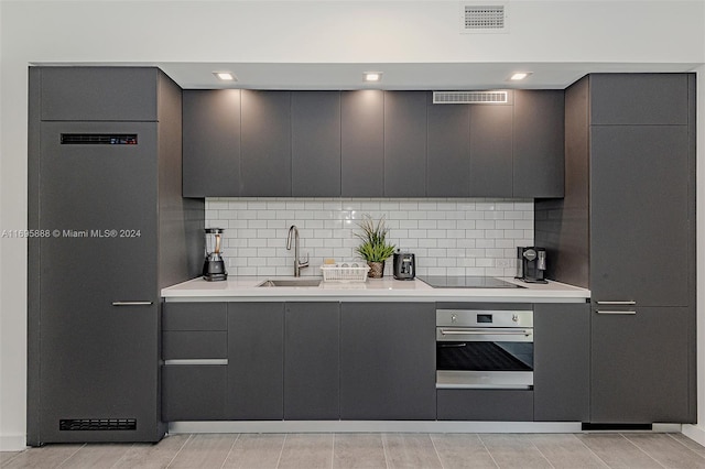 kitchen with backsplash, black electric cooktop, oven, and sink