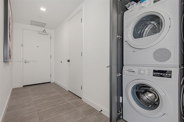 laundry area with light tile patterned floors and stacked washer / dryer