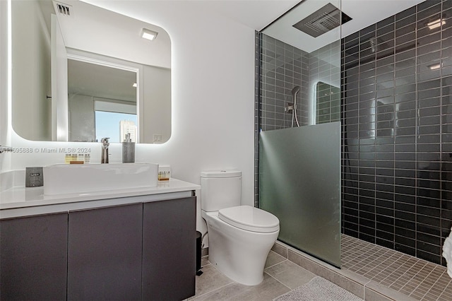 bathroom with tile patterned flooring, toilet, vanity, and tiled shower