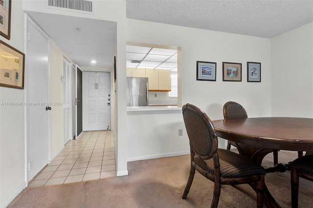 dining room with light carpet and a textured ceiling