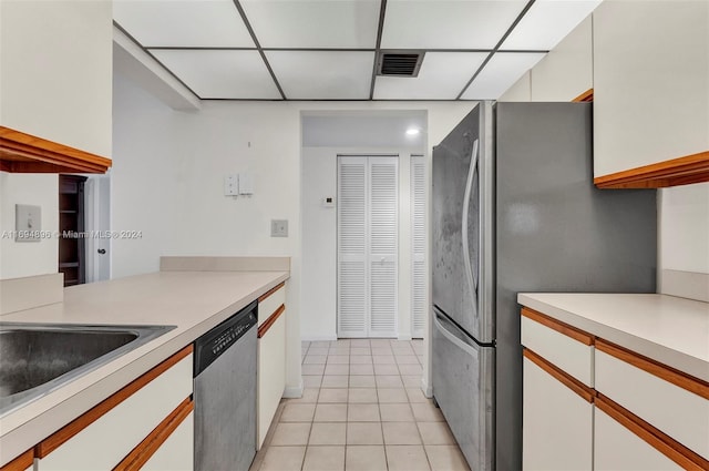 kitchen with white cabinets, a paneled ceiling, light tile patterned floors, and appliances with stainless steel finishes