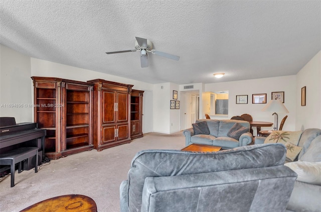 living room featuring light carpet, ceiling fan, and a textured ceiling