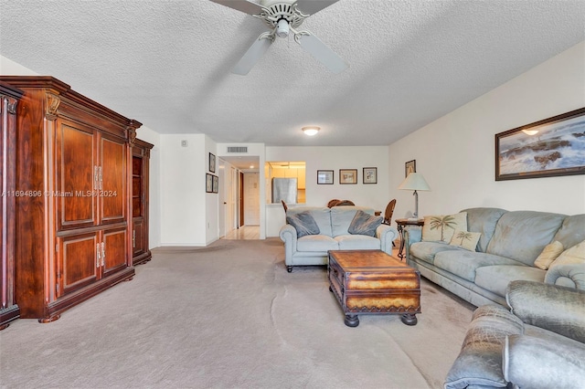 carpeted living room with ceiling fan and a textured ceiling