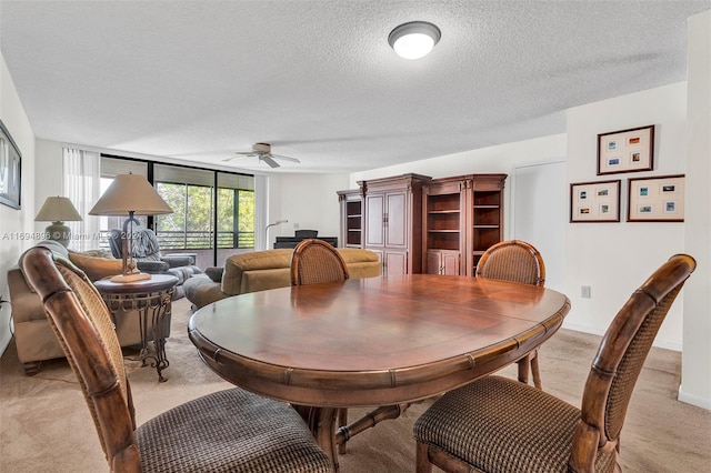 dining area with ceiling fan, light carpet, and a textured ceiling