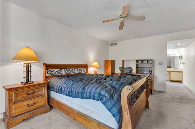 carpeted bedroom featuring a textured ceiling, ensuite bathroom, and ceiling fan